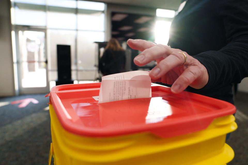 A poll location worker adds voting slips Tuesday, Nov. 8, 2022, to a bucket inside Radiant Bible Church in Avon, Indiana.