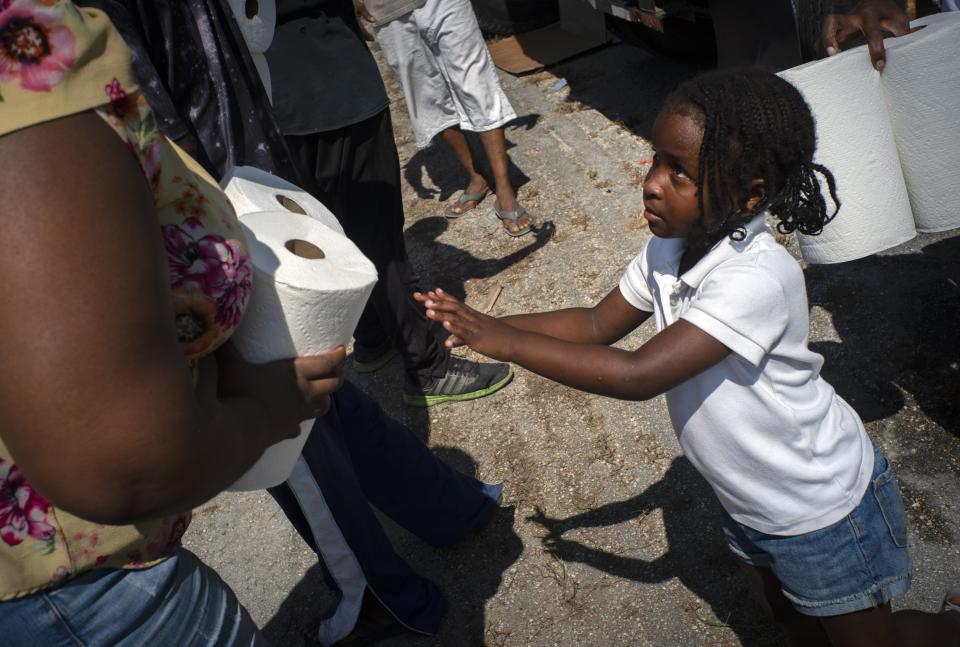 Five-year-old Cattleya Aranha helps to distribute paper rolls donated by private entities to victims of Hurricane Dorian, in Freeport, Bahamas, Saturday, Sept. 7, 2019. Search and rescue teams were still trying to reach some Bahamian communities isolated by floodwaters and debris Saturday after Hurricane Dorian struck the northern part of the archipelago last Sunday. (AP Photo/Ramon Espinosa)