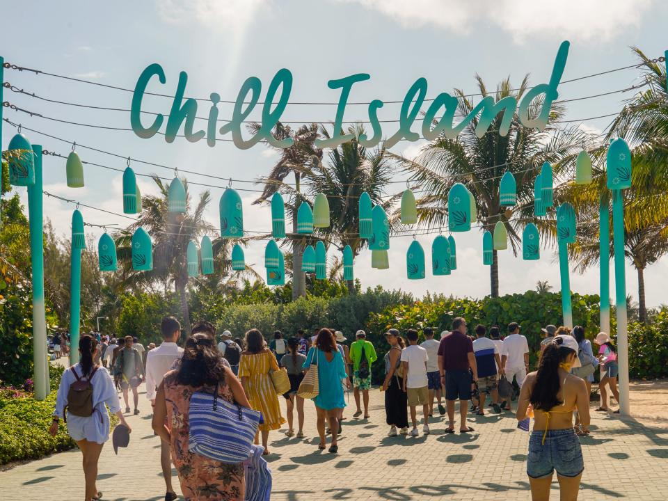 People walk through entrance to Chill Island at Coco Cay on a partly cloudy day