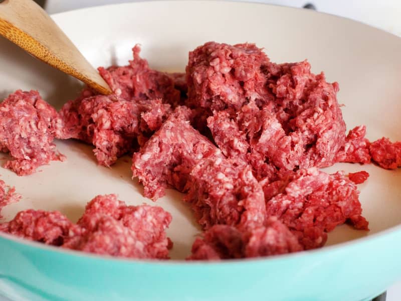 Woman stirring ground beef in a frying pan