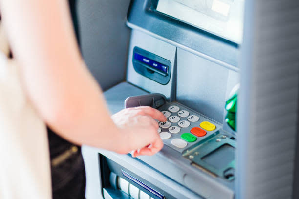 Person entering PIN code using ATM bank machine to withdraw money. Close-up. stock photo
