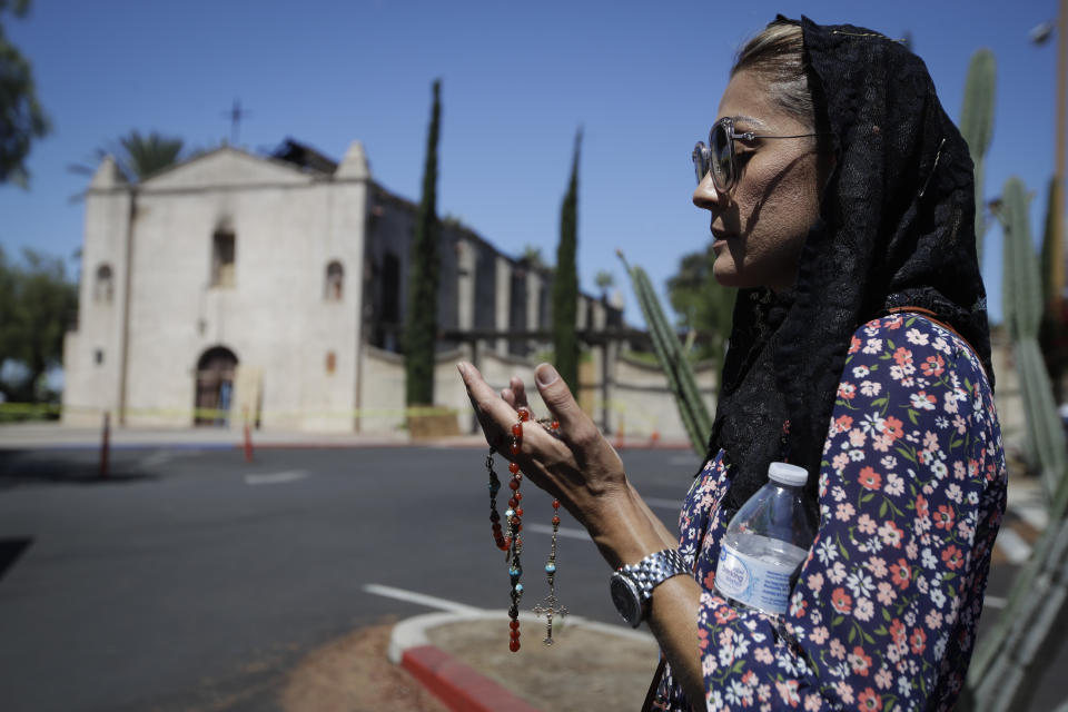 Alecia Ballin prays outside the fire-damaged San Gabriel Mission, Sunday, July 12, 2020, in San Gabriel, Calif. A fire on Saturday destroyed the rooftop and most of the interior of the nearly 250-year-old California church that was undergoing renovation. (AP Photo/Marcio Jose Sanchez)