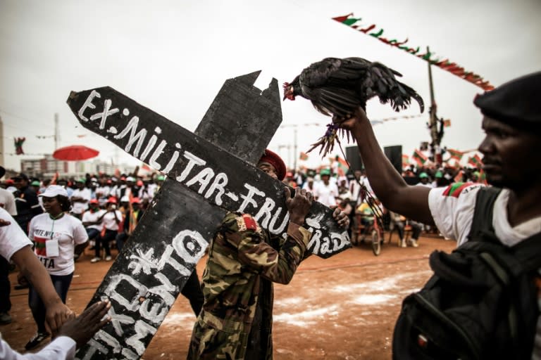 Supporters of Isaias Samakuva, presidential candidate for Angola's main opposition group UNITA, hold the party's symbol of a rooster and a cross attesting to the suffering of former military personnel, in Luanda on August 21, 2017