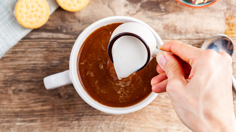 adding creamer to coffee