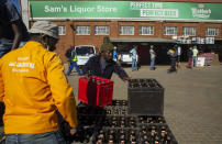 Workers load up purchased alcohol beverages at Sam Liquor Store in Thokoza township, near Johannesburg, South Africa, Monday, June 1, 2020. Liquor stores have reopened Monday after being closed for over two months under lockdown restrictions in a bid to prevent the spread of coronavirus. (AP Photo/Themba Hadebe)