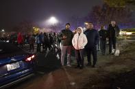 Pedestrians watch as a small plane rests on live power lines after crashing, Sunday, Nov. 27, 2022, in Montgomery Village, a northern suburb of Gaithersburg, Md. (AP Photo/Tom Brenner)