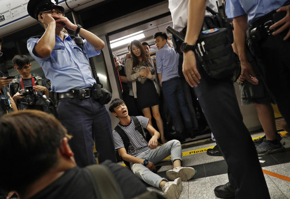 A protester, center, is surrounded by police officers while sitting on the floor saying he is injured at a subway platform in Hong Kong Wednesday, July 24, 2019. Subway train service was disrupted during morning rush hour after dozens of protesters staged what they called a disobedience movement to protest over a Sunday mob attack at a subway station. (AP Photo/Vincent Yu)