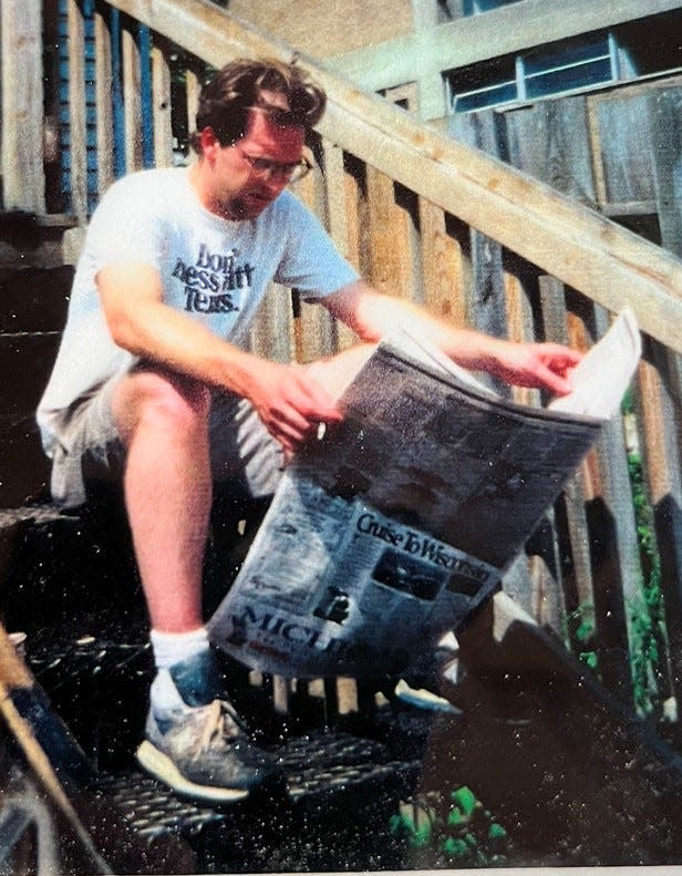 Shawn Windsor sitting on the back stoop of Angelo’s reading the newspaper.