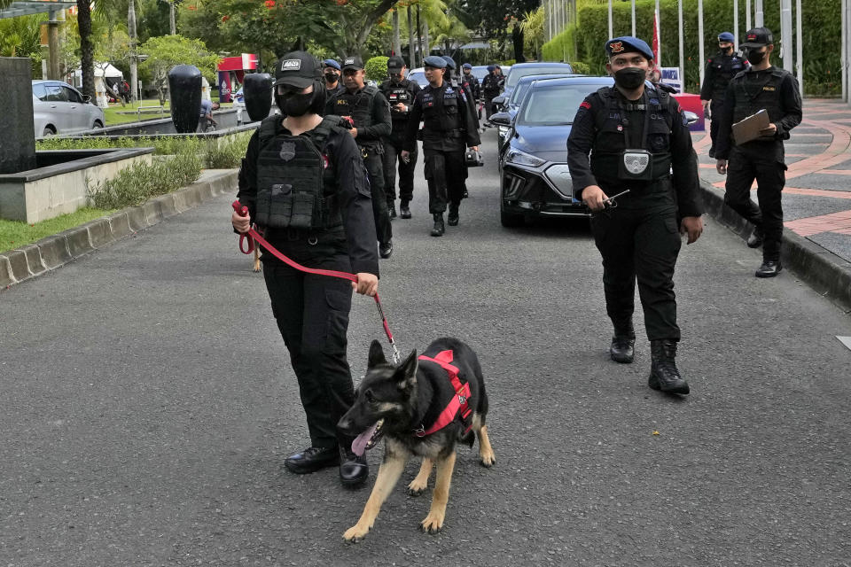 A police officer leads a sniffer dog ahead of the G20 Summit in Nusa Dua, Bali, Indonesia, Saturday, Nov. 12, 2022. Indonesia is gearing up to host the gathering of the leaders of the world's biggest economies this coming week. (AP Photo/Achmad Ibrahim)