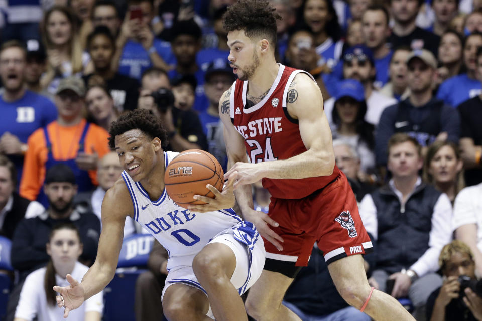 Duke forward Wendell Moore Jr. (0) reaches for the ball with North Carolina State guard Devon Daniels (24) during the first half of an NCAA college basketball game in Durham, N.C., Monday, March 2, 2020. (AP Photo/Gerry Broome)