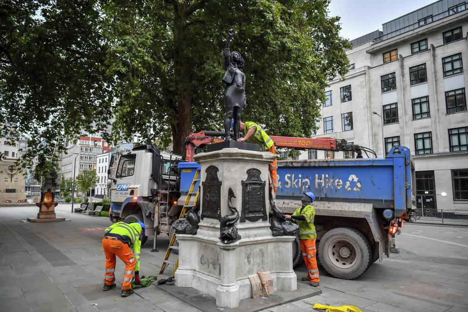 Contractors prepare to remove the statue "A Surge of Power (Jen Reid) 2020" by artist Marc Quinn, which had been installed on the site of the fallen statue of the slave trader Edward Colston, in Bristol, England, Thursday, July 16, 2020. The sculpture of protestor Jen Reid was installed without the knowledge or consent of Bristol City Council and was removed by the council 24 hours later. (Ben Birchall/PA via AP)