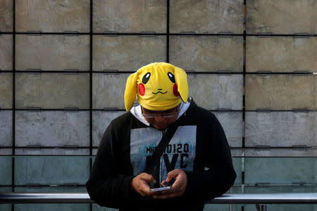 A man wearing a Pikachu hat, a character from Pokemon, plays Pokemon Go during a gathering to celebrate "Pokemon Day" in Mexico City, Mexico August 21, 2016. REUTERS/Carlos Jasso