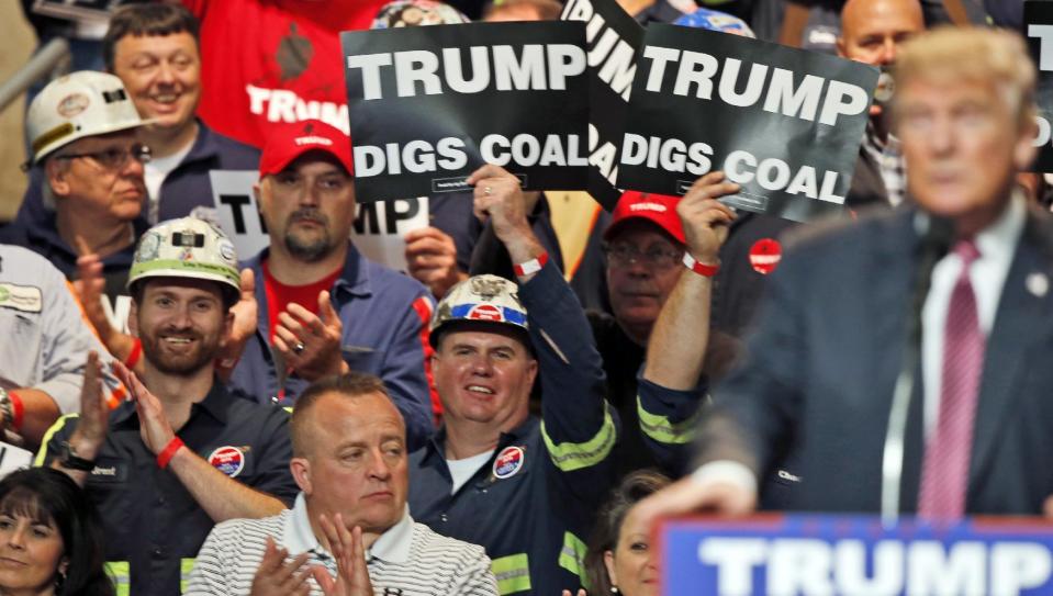 In this May 5, 2016 photo, coal miners wave signs as Republican presidential candidate Donald Trump speaks during a rally in Charleston, W.Va.(AP Photo/Steve Helber)