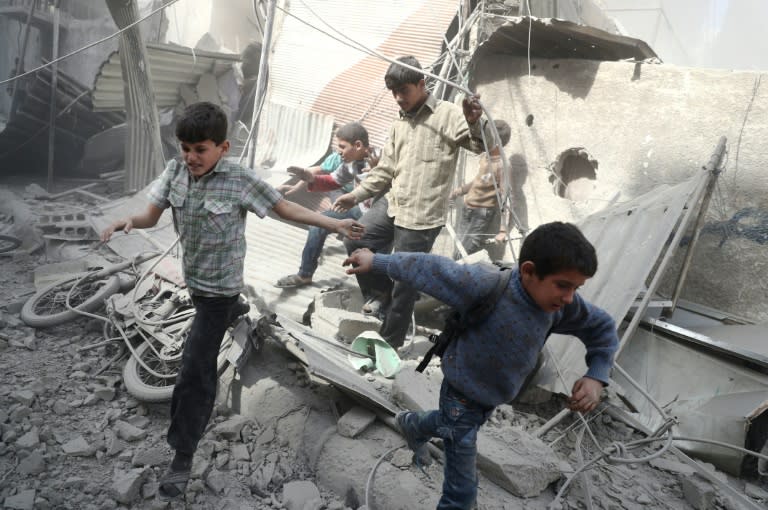 Syrian children run for cover following reported government air strikes on the rebel-held town of Douma, east of the Syrian capital Damascus, on October 26, 2016