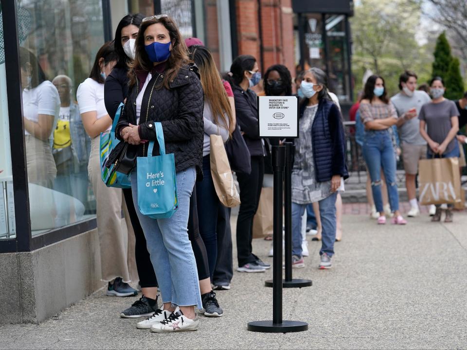 Shoppers wearing masks out of concern for the coronavirus wait outside a store on Boston's fashionable Newbury Street, Sunday, May 2, 2021.  (AP)