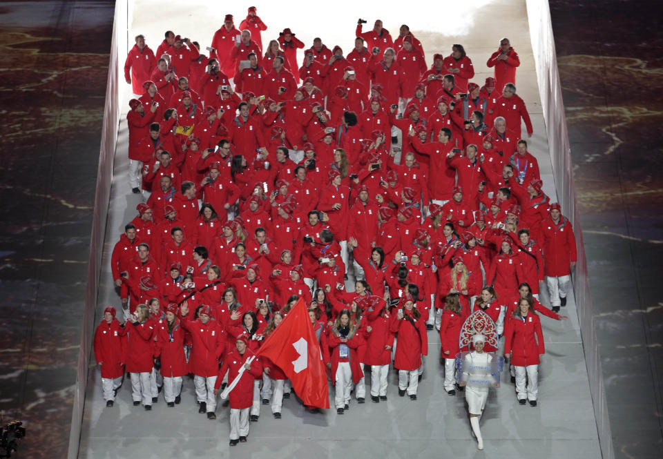 Simon Ammann of Switzerland holds his national flag and enters the arena with teammates during the opening ceremony of the 2014 Winter Olympics in Sochi, Russia, Friday, Feb. 7, 2014. (AP Photo/Charlie Riedel)