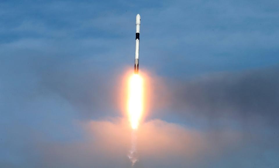 falcon 9 white and black rocket climbing in the blue sky with bright flame extending below its engines