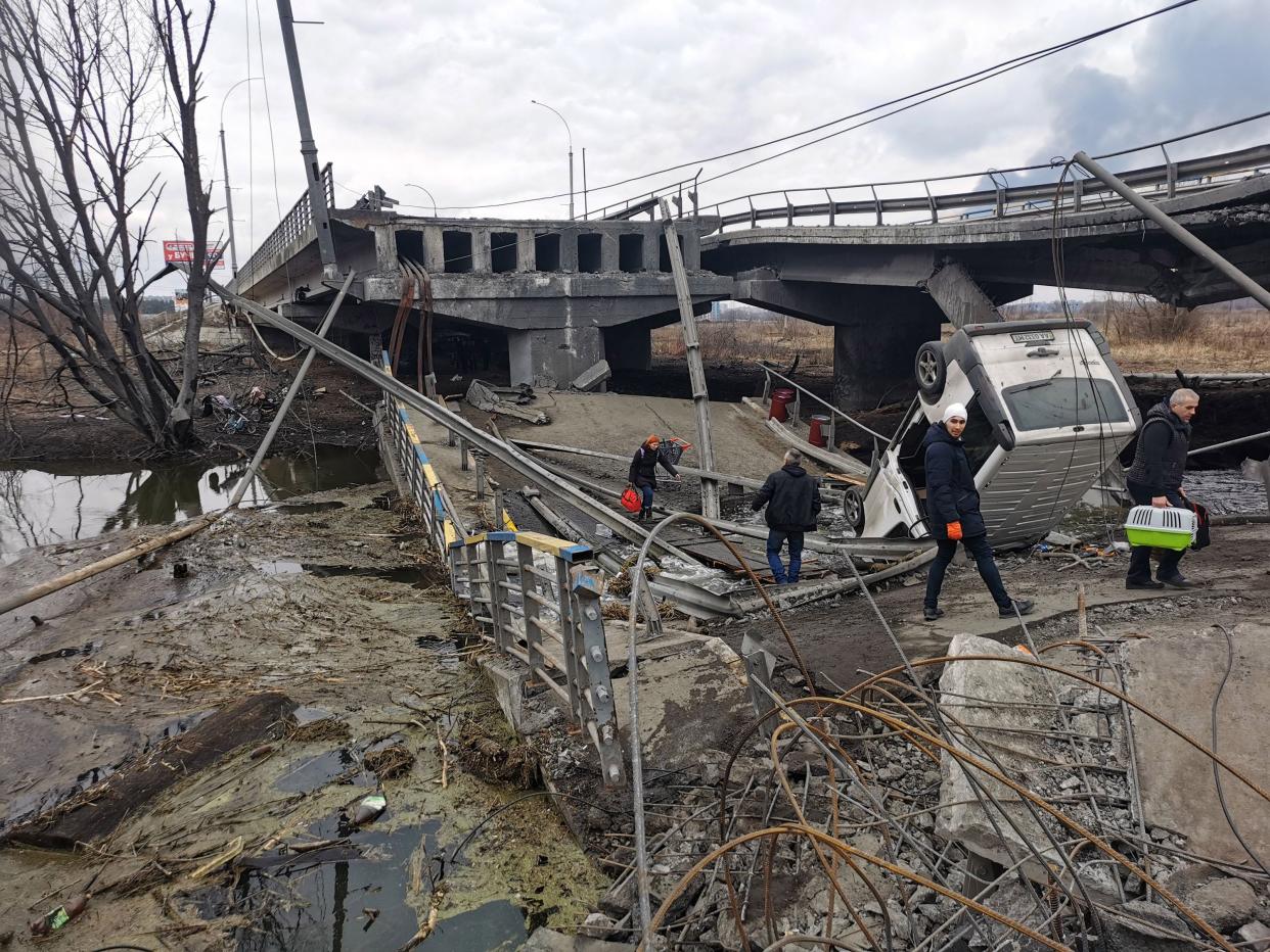 Pedestrians cross a destroyed bridge as they evacuate the city of Irpin, northwest of Kyiv, on March 6, 2022, 11 days after Russia launched a military invasion on Ukraine.