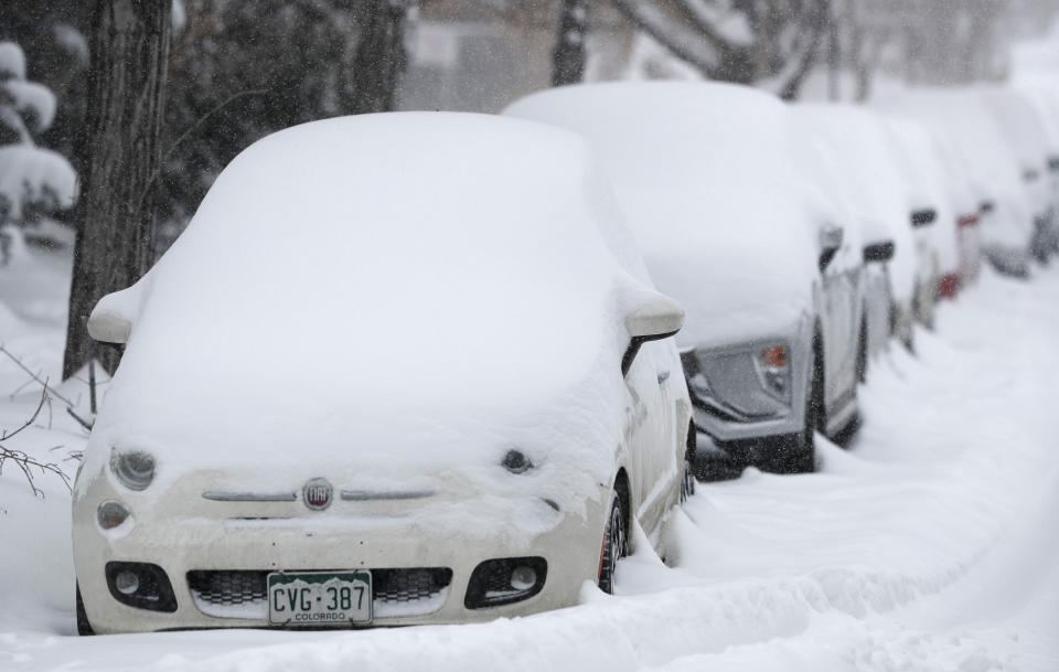 A long line of parked vehicles sits covered with snow as a snowstorm sweeps in over the region Tuesday, Nov. 26, 2019, in Denver. Stores, schools and government offices were closed or curtailed their hours while on another front, Thanksgiving Day travellers were forced to wrestle with snow-packed roads and flight delays or cancellations throughout the intermountain West. (AP Photo/David Zalubowski)