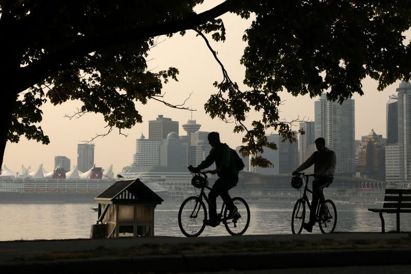 Cyclists pass the downtown core shrouded in a haze a wildfire smoke in Vancouver