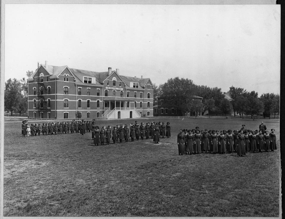 In this undated photo provided by National Archives, some students at the former Genoa Indian Industrial School in Genoa, Nebraska line up outside the school. Researchers are now trying to locate the bodies of more than 80 Native American children buried near the school in central Nebraska. For decades, the location of the student cemetery has been a mystery, lost over time after the school closed in 1931 and memories faded of the once-busy campus that sprawled over 640 acres in the tiny community of Genoa. (National Archives via AP)