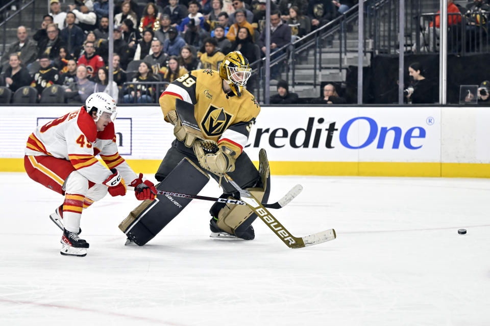 Calgary Flames left wing Jakob Pelletier (49) and Vegas Golden Knights goaltender Laurent Brossoit (39) battle for the puck during the third period of an NHL hockey game Thursday, Feb. 23, 2023, in Las Vegas. (AP Photo/David Becker)