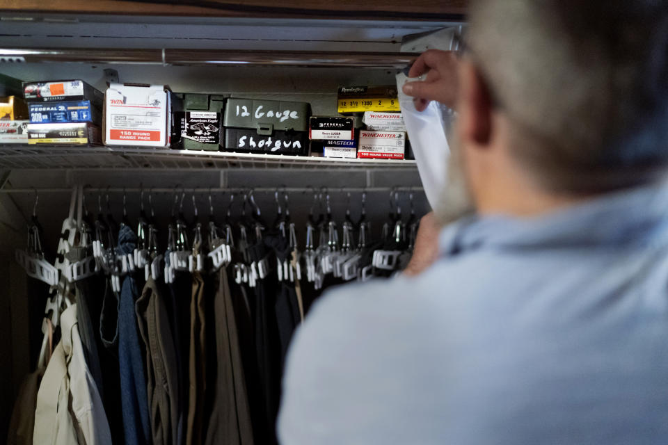 Mark Carlson pulls back a curtain to his wardrobe where he keeps ammunition in his home in Hammond, Wis., Wednesday, Sept. 28, 2022. The prospects of people taking up arms against their own government in response to draconian government crackdowns and firearm seizures seem distant and murky to Carlson. Still, they are spoken about. "I pray it will always be that the overthrow is at the ballot box," says Carlson, who seems genuinely pained at the idea of violence. "We don't want to use guns," he continues. "That would be just horrible." (AP Photo/David Goldman)