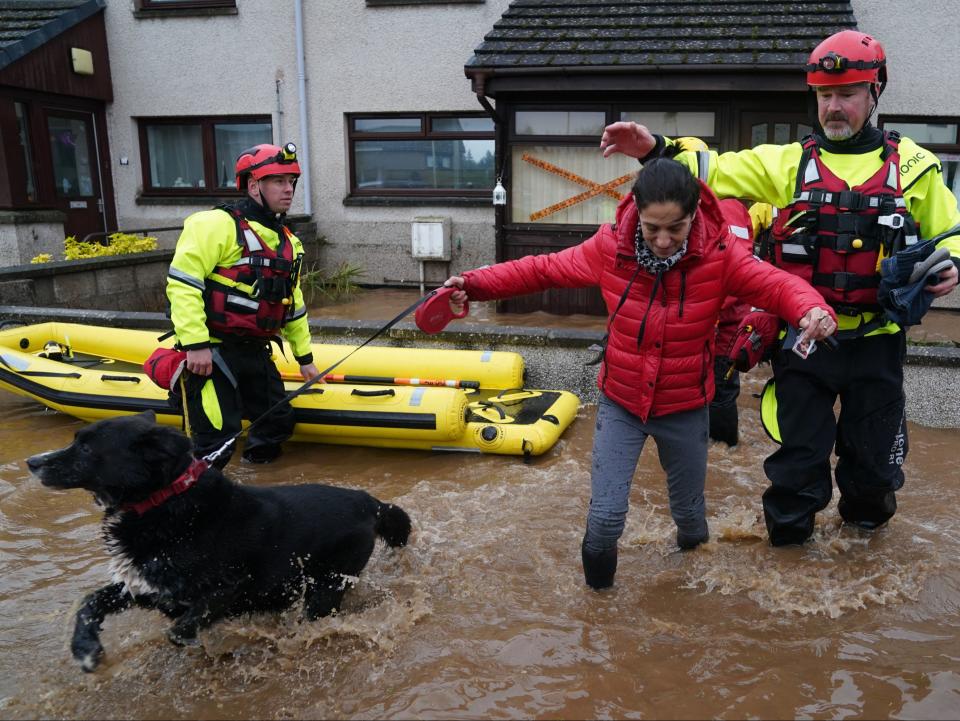 A resident is helped to leave her home in Brechin (PA)