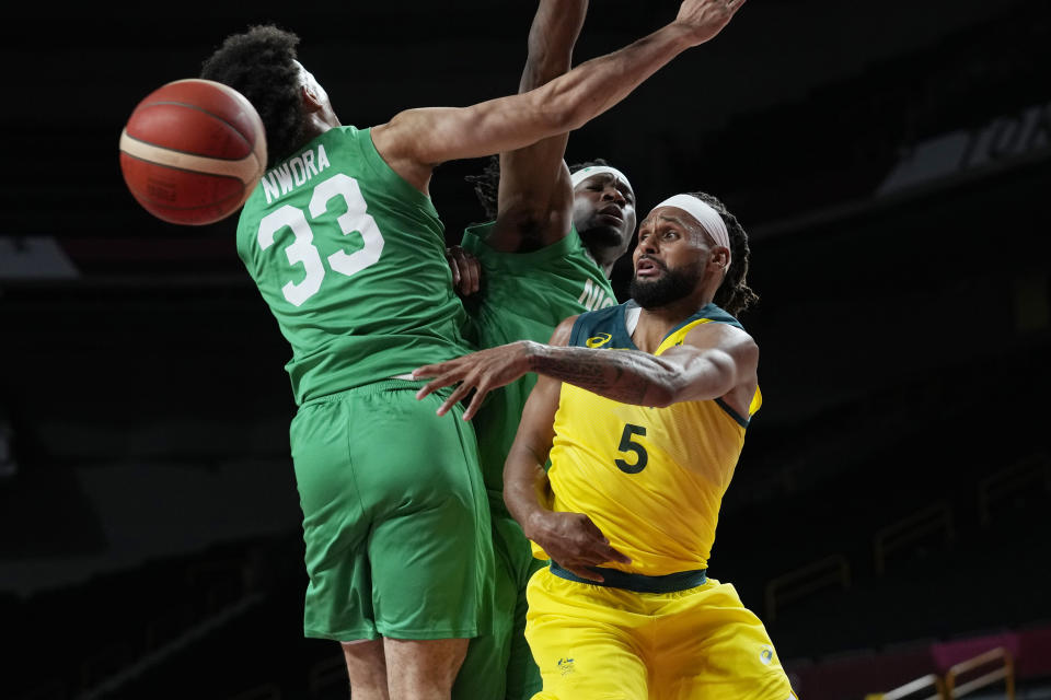 Australia's Patty Mills (5) passes the ball around Nigeria's Jordan Nwora (33) during a men's basketball preliminary round game at the 2020 Summer Olympics, Sunday, July 25, 2021, in Saitama, Japan. (AP Photo/Eric Gay)