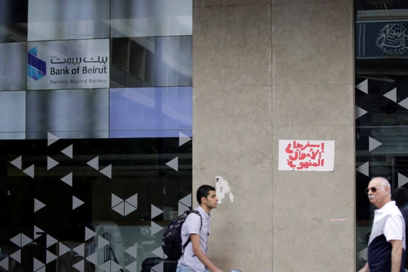 Two men walk past a closed bank office in Beirut