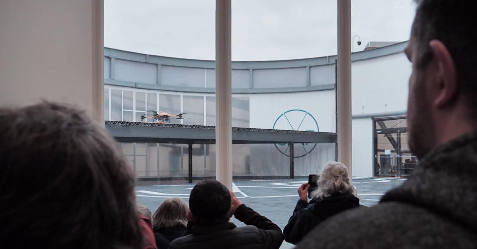 Spectators watch as an eVOTL aircraft lifts off from Britain's new Air-One eVOTL airport.