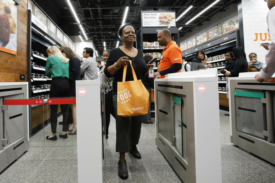 A customer carries her shopping bag as she walks out of a newly-opened Amazon Go store, Tuesday, May 7, 2019 in New York. The store will be the first Amazon Go store to accept cash. At its other shops, customers can only enter with an app that links to a credit card or an Amazon account.(AP Photo/Mark Lennihan)