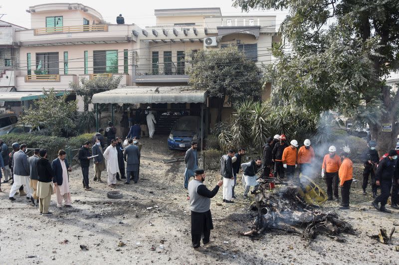 Police officers and rescue workers gather at the site of a suicide car bombing in Islamabad