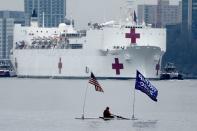 FILE PHOTO: The USNS Comfort pulls into Manhattan as a man rows past with a flag supporting U.S. President Donald Trump during the outbreak of coronavirus disease (COVID-19), in the Manhattan borough of New York City