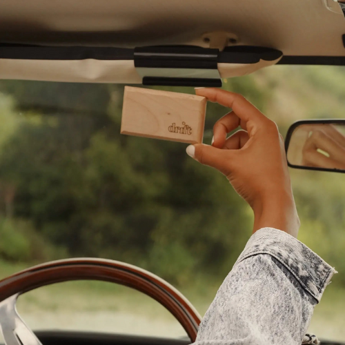 hand holding up drift car freshener while driving