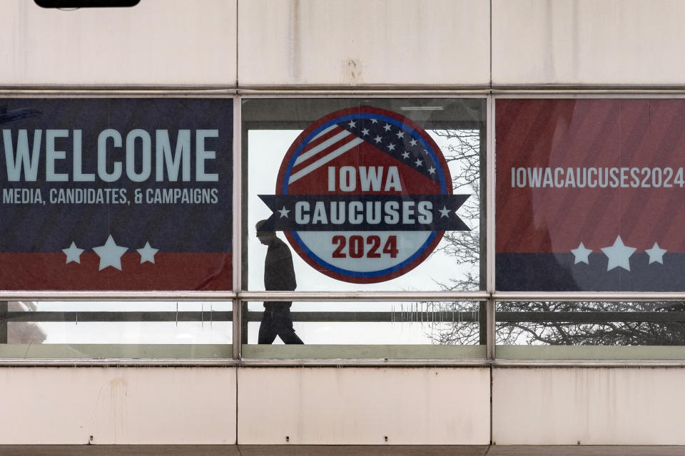 A man walks past a sign that reads "Iowa Caucuses 2024" in downtown Des Moines, Iowa, Saturday, Jan. 13, 2024. (AP Photo/Andrew Harnik)