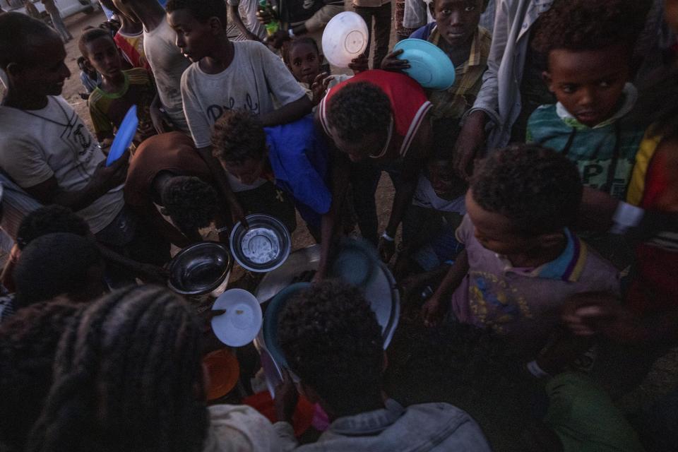 Tigray men who fled the conflict in Ethiopia's Tigray region, receive cooked rice from charity organization Muslim Aid, at Umm Rakouba refugee camp in Qadarif, eastern Sudan, Friday, Nov. 27, 2020. Ethiopian Prime Minister Abiy Ahmed again ruled out dialogue with the leaders of the defiant Tigray region Friday but said he was willing to speak to representatives "operating legally" there during a meeting with three African Union special envoys trying to end the deadly conflict between federal troops and the region's forces. (AP Photo/Nariman El-Mofty)