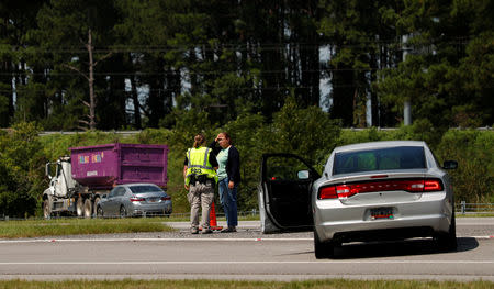 A South Carolina State Trooper is seen talking to a motorist as she stopped alongside Interstate 26 ahead of the arrival of Hurricane Florence near Orangeburg, South Carolina, U.S., September 11, 2018. REUTERS/Chris Keane