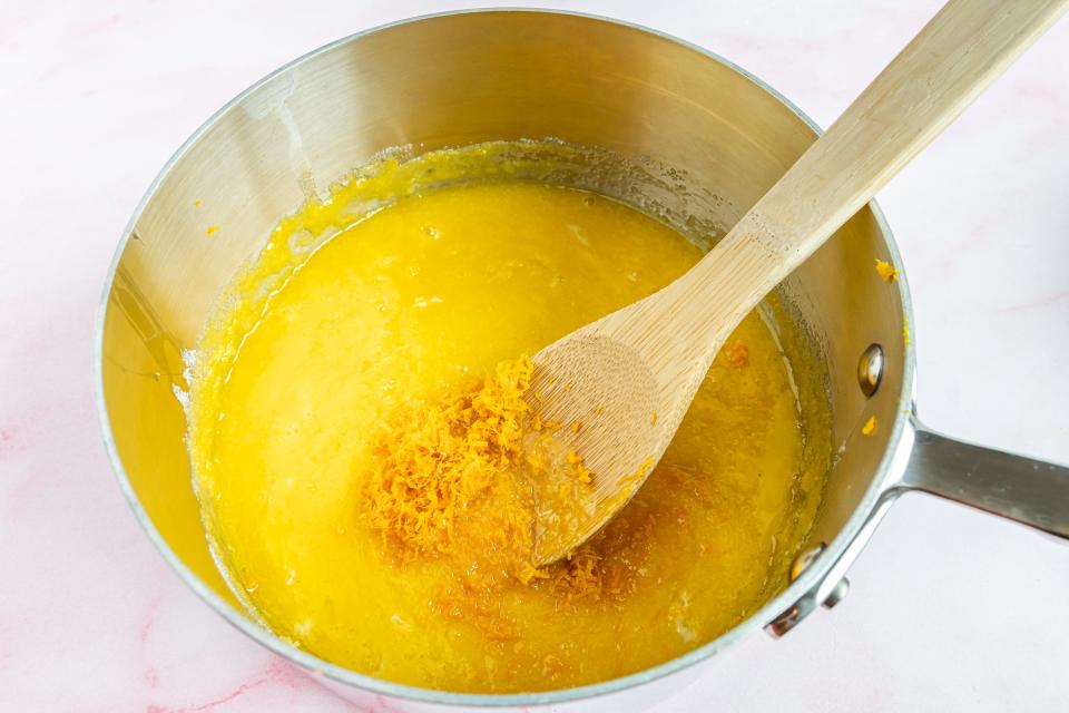 adding citrus zest to eggs with wooden spoon