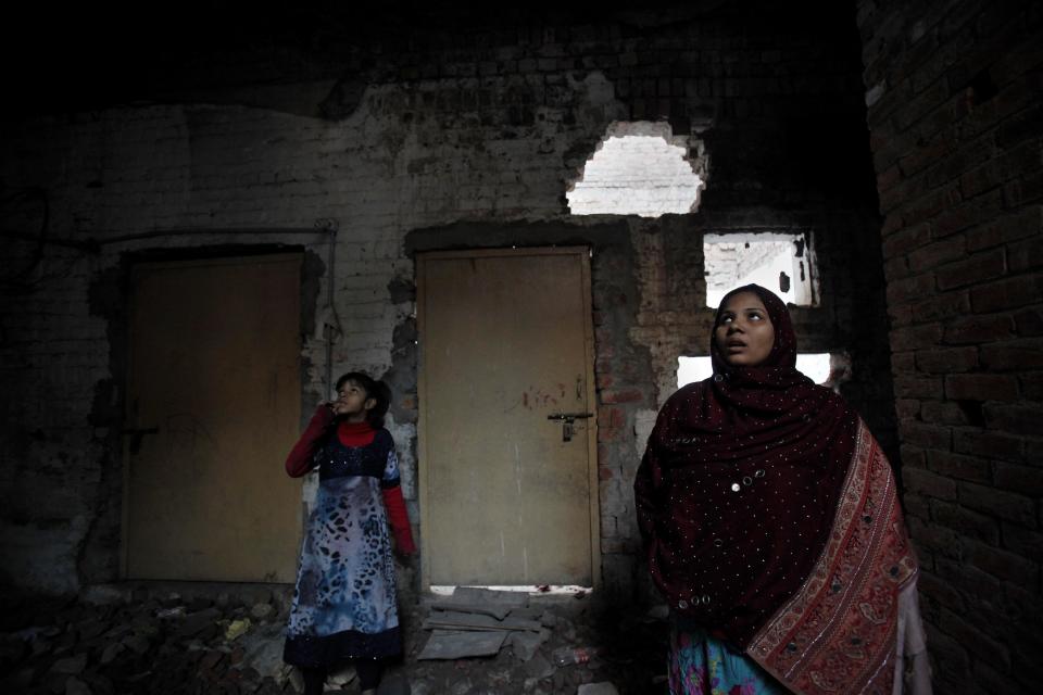 In this Saturday, Jan. 11, 2014, photo, Pakistani Christian, Nomi Shahid and her daughter Aliza, stand at their house, which was torched by radical Muslim's mob last March, in Lahore. Pakistan’s blasphemy law has become a potent weapon in the arsenal of Muslim extremists, who use it against adherents of minority religions. (AP Photo/Anjum Naveed)