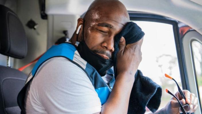 Muž v kabině kamionu utírá pot z čela ručníkem