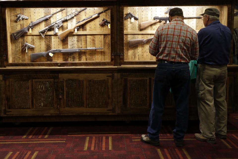Attendees look over a wall of guns available to win in a raffle at the National Rifle Association's annual convention in Friday, April 25, 2014 in Indianapolis. Several potential Republican contenders for president will court gun-rights supporters at the NRA's annual convention Friday. (AP Photo/AJ Mast)