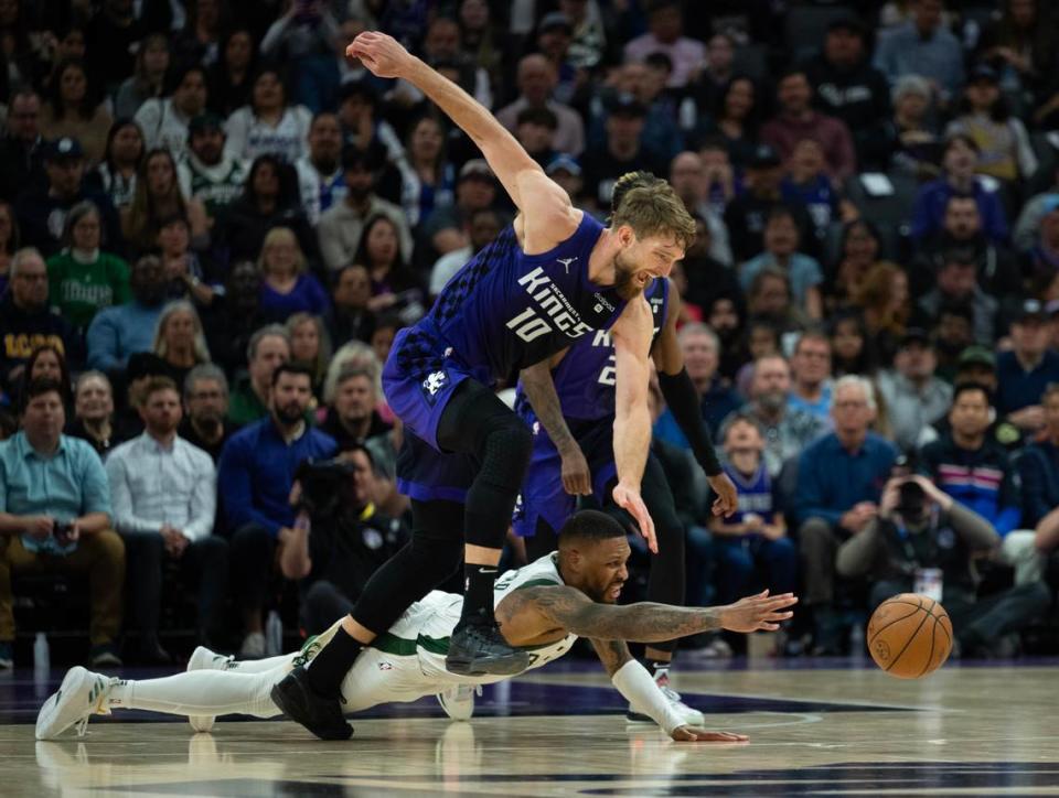 Sacramento Kings center Domantas Sabonis battles Milwaukee Bucks guard Damian Lillard (0) for a loose ball Tuesday, March 12, 2024, at Golden 1 Center in Sacramento.