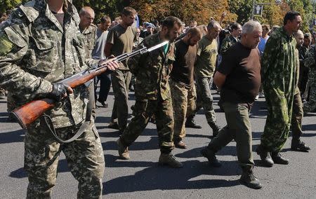 An armed pro-Russian separatist (L) escorts a group of Ukrainian prisoners of war as they walk across central Donetsk August 24, 2014. REUTERS/Maxim Shemetov