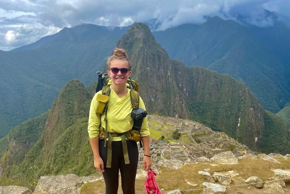 Author Nicole Jordan smiling at a summit in front of mountains on a hike