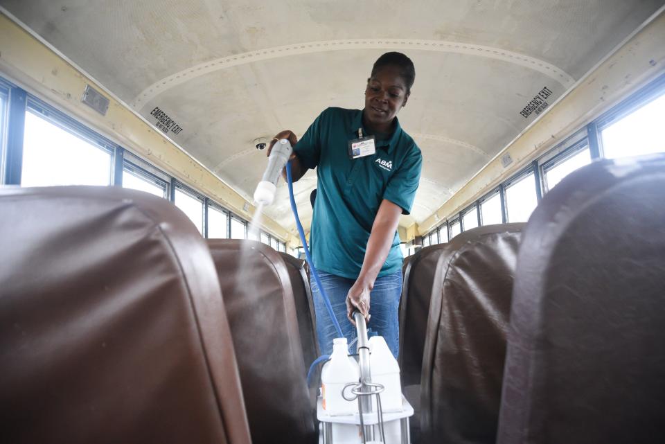 Regina Jones, with American Building Maintenance, disinfects a Vicksburg Warren School District school bus to combat the coronavirus, Friday, March 13, 2020, in Vicksburg, Miss. (Courtland Wells/The Vicksburg Post via AP)