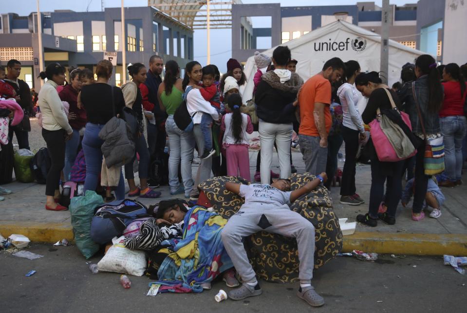 Venezuelan migrants rest while another group stands in line to enter am immigration office in Tumbes, Peru, Friday, June 14, 2019. Venezuelan citizens are rushing to enter Peru before the implementation of new entry requirements on migrants fleeing the crisis-wracked South American nation. (AP Photo/Martin Mejia)