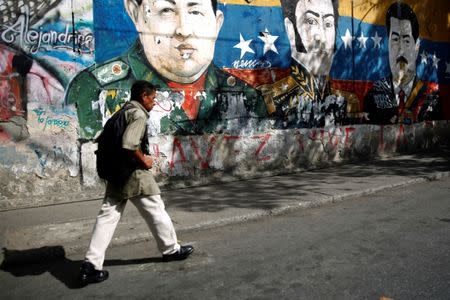A man walks by graffiti of South American revolutionary hero Simon Bolivar, Venezuela's late President Hugo Chavez and Venezuela's President Nicolas Maduro at the Jose Felix Ribas neighborhood in Caracas, Venezuela January 30, 2019. REUTERS/Carlos Barria
