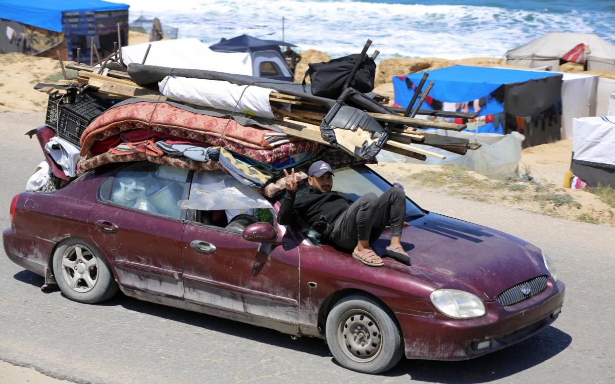 A man sits on the bonnet of an overloaded car