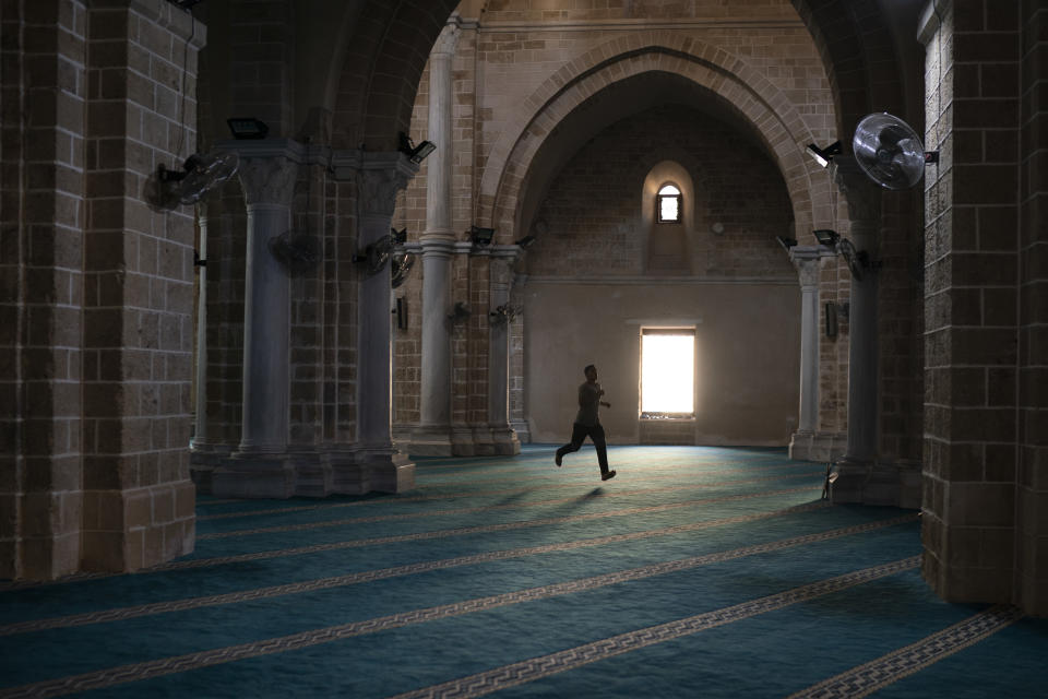 In this Friday, Sept. 14, 2018 photo, a man runs as he arrives a few minutes late for the afternoon prayer in a mosque in Gaza City. After Friday prayers around 4 p.m., Hamas dispatches huge buses to many mosques to bring supporters to the border. But many more come on their own -- on foot, in cars, motorcycles, bikes and wheelchairs. (AP Photo/Felipe Dana)